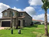 Two-story house with a gray exterior, two-car garage, and a neatly landscaped lawn at 5465 Misty Oak Cir, Davenport, FL 33837