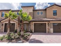 Inviting townhome with a brick driveway, stone accents, and mature landscaping at 8976 Azalea Sands Ln # 2604, Davenport, FL 33896