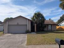 One-story house with attached garage, palm tree, and a well-maintained lawn at 12142 Caper St, Orlando, FL 32837