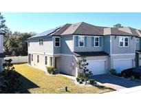 Modern townhome featuring a gray exterior, attached garage, and professionally landscaped yard at 15079 Willow Arbor Cir, Orlando, FL 32824