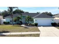 Light teal house with a two-car garage and palm trees at 509 Drayton Rd, Winter Haven, FL 33884