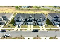 Aerial view of the gray townhomes featuring attached garages, black shutters, and community pool in the background at 697 Stoney Point Cir, Davenport, FL 33896