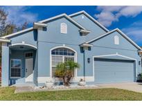 Beautiful blue house with a two-car garage and well-manicured lawn at 9850 Hidden Dunes Ln, Orlando, FL 32832