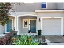 Townhouse exterior featuring a gray facade, two-car garage, and landscaping at 2106 Crystal Bell St, Orlando, FL 32824