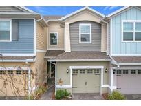 Two-story townhome with light-grey and blue siding, and a two-car garage at 2559 Sedge Grass Way, Orlando, FL 32824