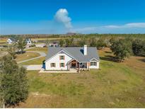 Aerial view of a charming farmhouse on a spacious lot with mature trees at 3449 N Canoe Creek Rd, Kenansville, FL 34739
