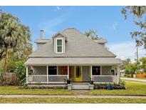 Charming two-story home featuring a cozy front porch, bright yellow door, and beautifully landscaped front yard at 723 New York Ave, St Cloud, FL 34769