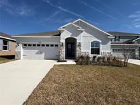Single-story home with white exterior, stone accents, and a two-car garage at 835 Griffon Ave, Lake Alfred, FL 33850