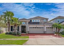 Two-story house with a gray exterior, red brick driveway, and palm trees at 3040 Cardillino Way, Kissimmee, FL 34741