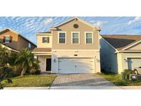 Charming two-story home with a large garage and a well-manicured lawn and a paver driveway at 4571 Tribute Trl, Kissimmee, FL 34746