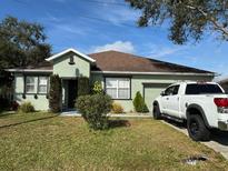 One-story house with a brown roof and green exterior, a yard, and a truck parked in the driveway at 626 Baldwin Dr, Kissimmee, FL 34758