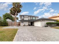 Charming two-story home with a well-manicured lawn, brick driveway, and a serene landscape with mature trees at 13008 Baltimore Woods Ln, Orlando, FL 32824
