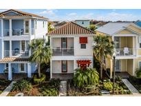 Charming two-story home with a balcony, red accents and a neatly landscaped front yard with palms at 2979 Latitude Ln, Kissimmee, FL 34747