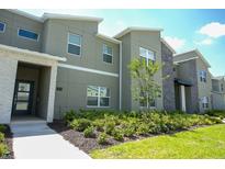 Modern townhome with a well-maintained landscape and stone detailing at 750 Pebble Beach Dr, Davenport, FL 33896