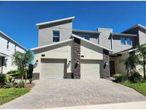 Modern townhome boasts a two-car garage, stone accents, and a neutral color scheme, exuding curb appeal at 8885 Cabot Cliffs Dr # 103, Davenport, FL 33896