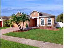 Charming single-story home with well-manicured lawn, palm trees, and a brick driveway at 1728 Plantation Pointe Dr, Orlando, FL 32824