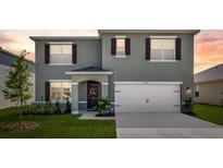 Two-story home featuring a two-car garage, manicured lawn, and charming front entrance at 1755 Buckeye Rd, Davenport, FL 33837