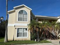 Inviting two-story condo featuring arched windows, a covered entryway, and lush tropical landscaping at 2314 Prime Cir # B, Kissimmee, FL 34746