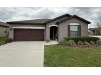 Charming single-story home with a well-manicured lawn, dark brown garage door, and neutral exterior paint at 8835 Conway Rd, Polk City, FL 33868
