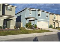 Charming two-story home boasts blue exterior, well-manicured lawn, and a two-car garage at 1292 Cascades Ave, Davenport, FL 33837