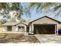 Charming single-story home featuring a modern white and black exterior, new driveway, and a two-car garage at 2488 Pine Chase Cir, St Cloud, FL 34769