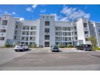 View of a modern condo building with well-maintained landscaping and ample parking under a sunny sky at 3180 Paradoux Circle # 205, Kissimmee, FL 34746