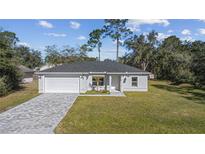 Charming single-story home boasts a well-manicured lawn and a gray brick driveway, under a bright blue sky at 6495 Eve St, St Cloud, FL 34771