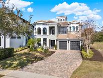 Beautiful, grand home featuring a three-car garage, tile roof, and a well-manicured lawn at 7471 Gathering Loop, Reunion, FL 34747