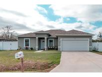 Charming single-story home with a well-manicured lawn and a two-car garage with driveway at 125 Inconnu Ct, Poinciana, FL 34759