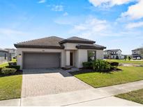 Well-maintained one-story home with brick driveway, two car garage, and lush green lawn at 194 Aidans Lndg, Haines City, FL 33844