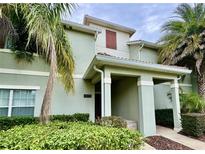 Inviting two-story townhouse with lush landscaping and a covered front entrance at 4875 Clock Tower Dr, Kissimmee, FL 34746