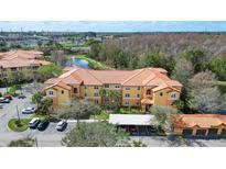 Aerial view of multi-Gathering home complex with a pond, fountain, mature trees, and covered parking at 5463 Vineland Rd # 5107, Orlando, FL 32811