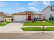 Charming single-story home with a well-manicured lawn, a two car garage, and a red front door at 758 Lafayette Ln, Haines City, FL 33844