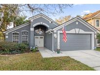 Charming gray single-Gathering home featuring an arched entryway, well-maintained lawn, and a two-car garage at 816 Garden Glen Loop, Lake Mary, FL 32746