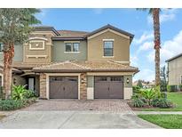 Inviting two-story townhome featuring a brick driveway and attached two-car garage at 8946 Azalea Sands Ln # 8946, Davenport, FL 33896