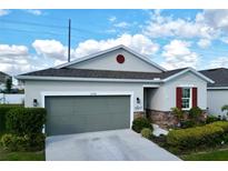 Charming one-story home featuring a gray garage door, stone accents, and well-manicured landscaping at 1042 Heirloom Dr, Haines City, FL 33844