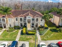 Inviting condo building featuring lush landscaping, red tile roof, and convenient parking spaces at 13829 Timberland Dr # 204, Orlando, FL 32824