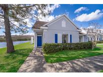 Charming single-story home with a blue door and shutters, complemented by lush landscaping and water view at 2022 Island Walk Dr, Orlando, FL 32824