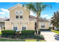 Inviting two-story home featuring a well-manicured lawn, lush landscaping, and a mature palm tree at 240 Minniehaha Cir, Haines City, FL 33844