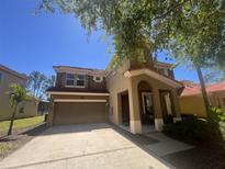 Two story tan home with a two car garage and a terracotta colored roof under a clear blue sky at 375 Orange Cosmos Blvd, Davenport, FL 33837