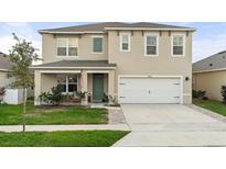 Charming two-story home features a well-manicured lawn, attached two-car garage, and welcoming front porch at 6808 Cranes Roost Rd, Harmony, FL 34773
