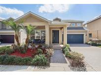 Charming tan home featuring a lush landscaped yard, front porch seating area, and a two-car garage at 13258 Vennetta Way, Windermere, FL 34786