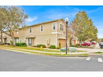 Two-story townhome featuring a beige exterior, attached garage, manicured landscaping and mature trees at 1518 Orrington Payne Pl, Casselberry, FL 32707