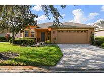 Charming single-story home with lush lawn, mature trees, and a brick-paved driveway leading to a two-car garage at 159 Ventana Dr, Kissimmee, FL 34759