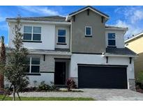 Two-story home showcasing a sleek, modern design with a dark gray garage door and neutral color palette at 2402 Rama Dr, Kissimmee, FL 34746