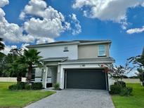 Two-story home boasts a brick paved driveway, dark garage door, manicured lawn, and well maintained landscaping at 2641 Calistoga Ave, Kissimmee, FL 34741