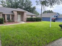 Traditional brick home featuring a well-maintained lawn, manicured bushes, and mature shade trees at 3216 Fieldcrest Ter, Deltona, FL 32725