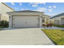 View of the garage, driveway, and front lawn with landscaping at 3930 Palazzo Pl, Winter Haven, FL 33884