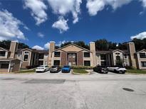 Condo building exterior with ample parking and neatly landscaped grounds on a sunny day at 5587 Devonbriar Way # 106, Orlando, FL 32822