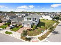 New two-story home featuring a brick driveway, attached two-car garage and manicured landscaping at 6699 Alder Rd, Harmony, FL 34773